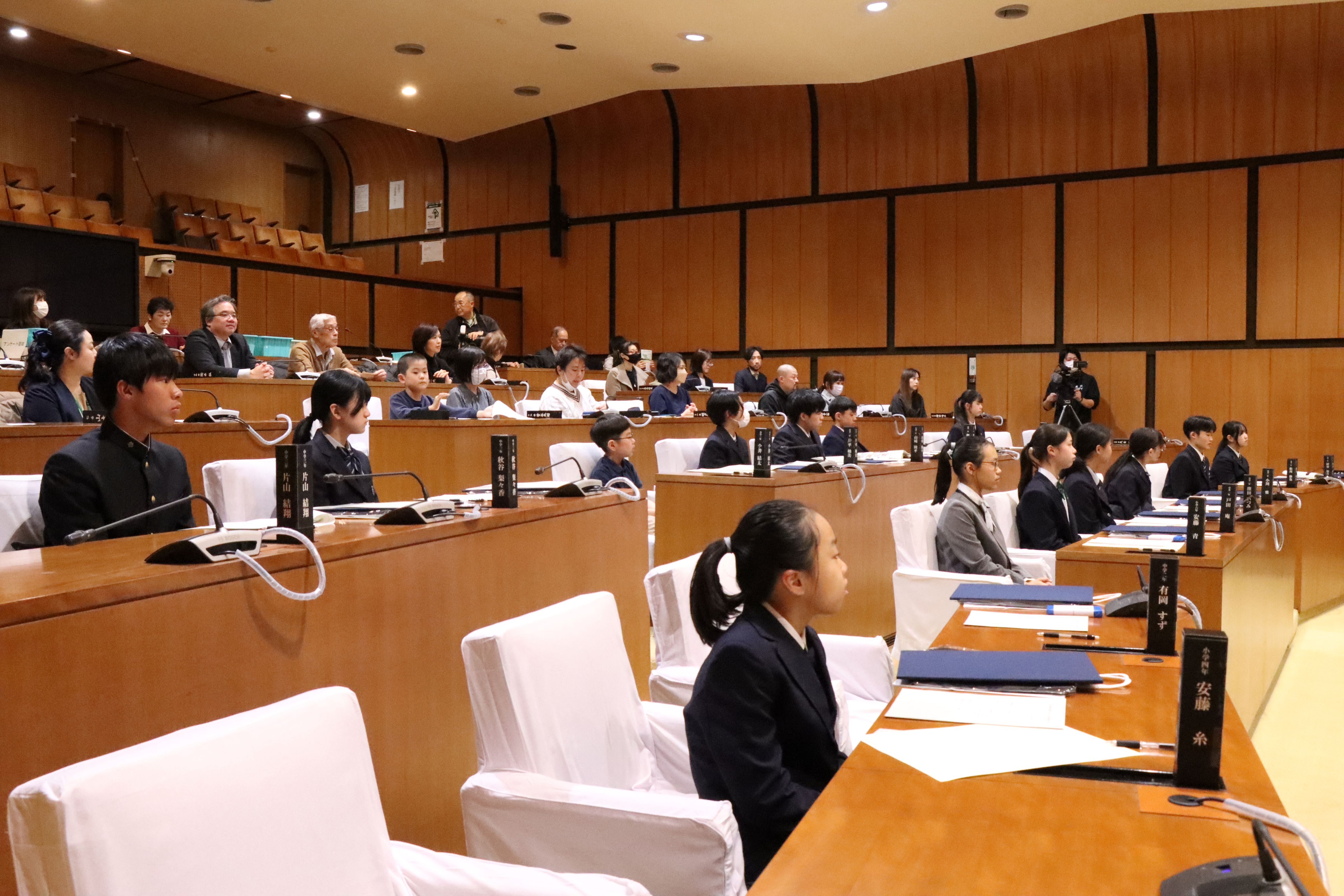 議場で立札の前に座る受賞者たち